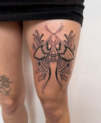 a woman with a moth tattoo on her thigh